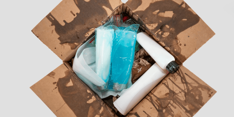 Leaked liquid product bottles inside a shipping box with soaked and damaged packaging materials. 