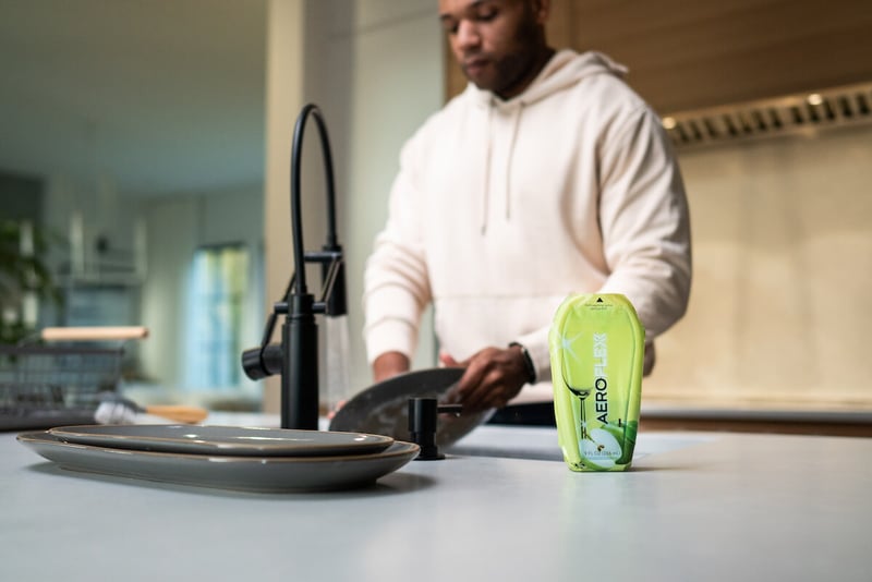 Man washing dishes with an AeroFlexx Pak on the counter