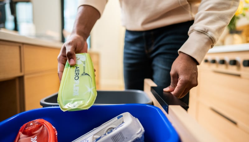 Gentleman recycling an AeroFlexx pak into the kitchen's recycling bin.